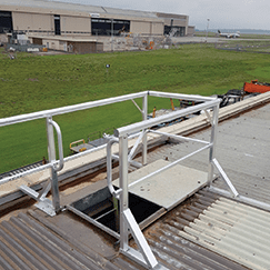Roof access hatch with sliding lid and permanent guardrail for edge protection